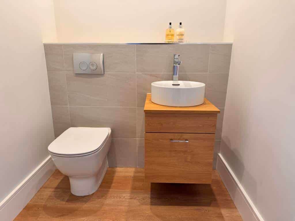 Compact cloakroom Fitted bathroom furniture, including a wall-hung toilet and a single oak vanity with a round vessel sink.