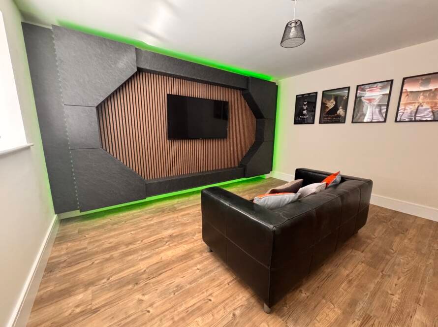Modern media wall unit with geometric panel design, wall-mounted TV, wood slat centre, and green LED backlighting in a contemporary living room.