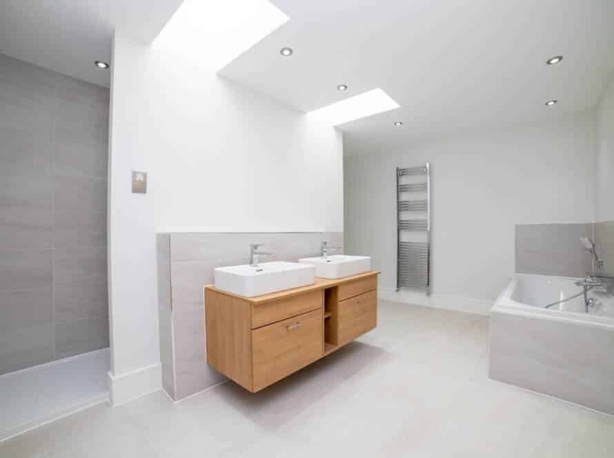 Full suite of fitted bathroom furniture including a double vanity, matching tiled bathtub surround, and integrated shower wall.